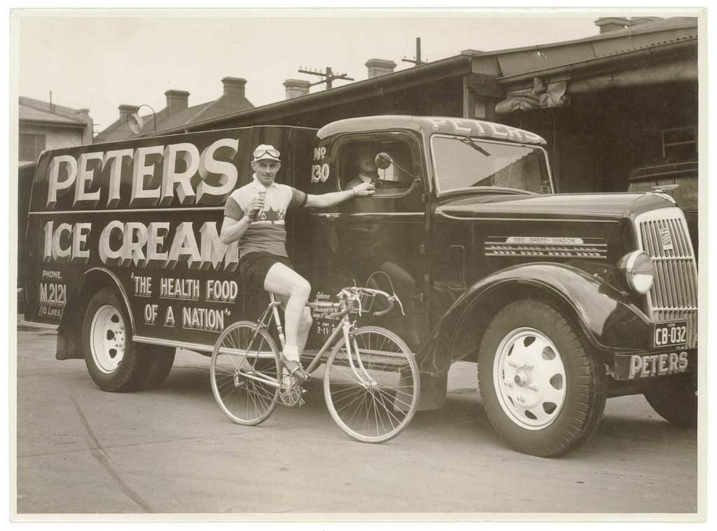 Hubert Opperman eating an ice cream next to a Peter's Ice Cream Reo truck,1936, by Sam Hood