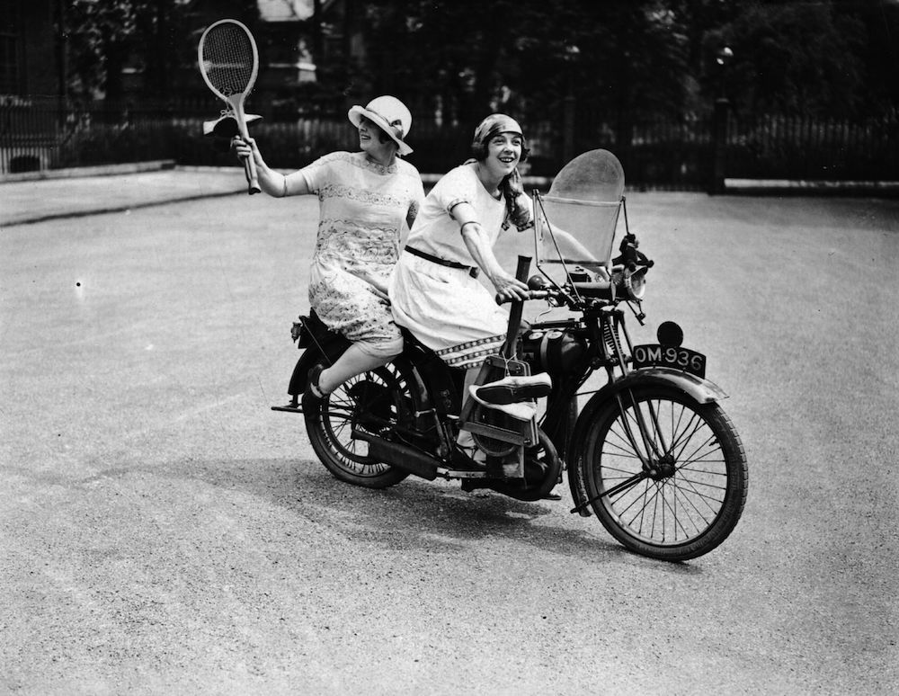 1925:  Two women set off on a BSA motorbike to play tennis after work.  (Photo by Topical Press Agency/Getty Images)