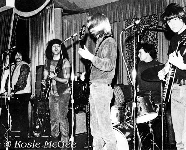 The Grateful Dead performing at Troupers Hall in Los Angeles on March 25, 1966. This show is often listed as an Acid Test, but it was not, according to photographer Rosie McGee. From left to right: Pigpen, Garcia, Lesh, Kreutzmann, and Weir.