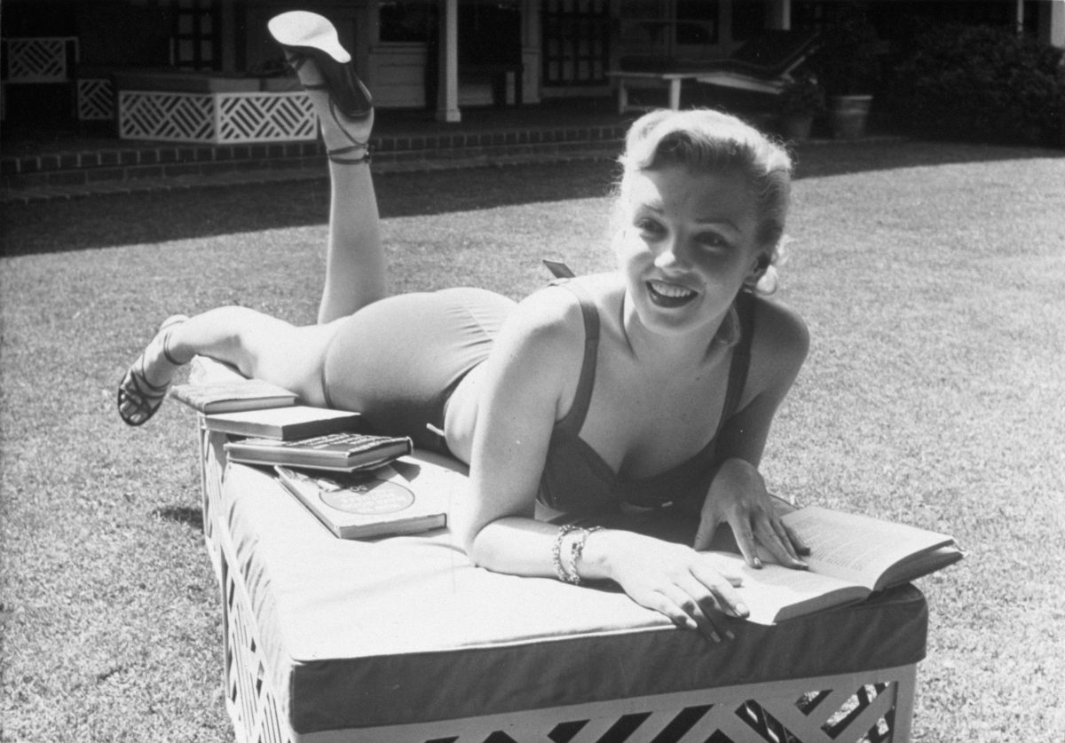 FILM STILLS OF 1950, BACKYARD, BATHING SUIT, CLOTHING, HOME, MARILYN MONROE, PIN-UPS, READING, BOOKS, CLEAVAGE, SWIM SUIT, SUN BATHING, SUN BAKING, SUNNY, EXTERIOR IN 1950 VARIOUS
