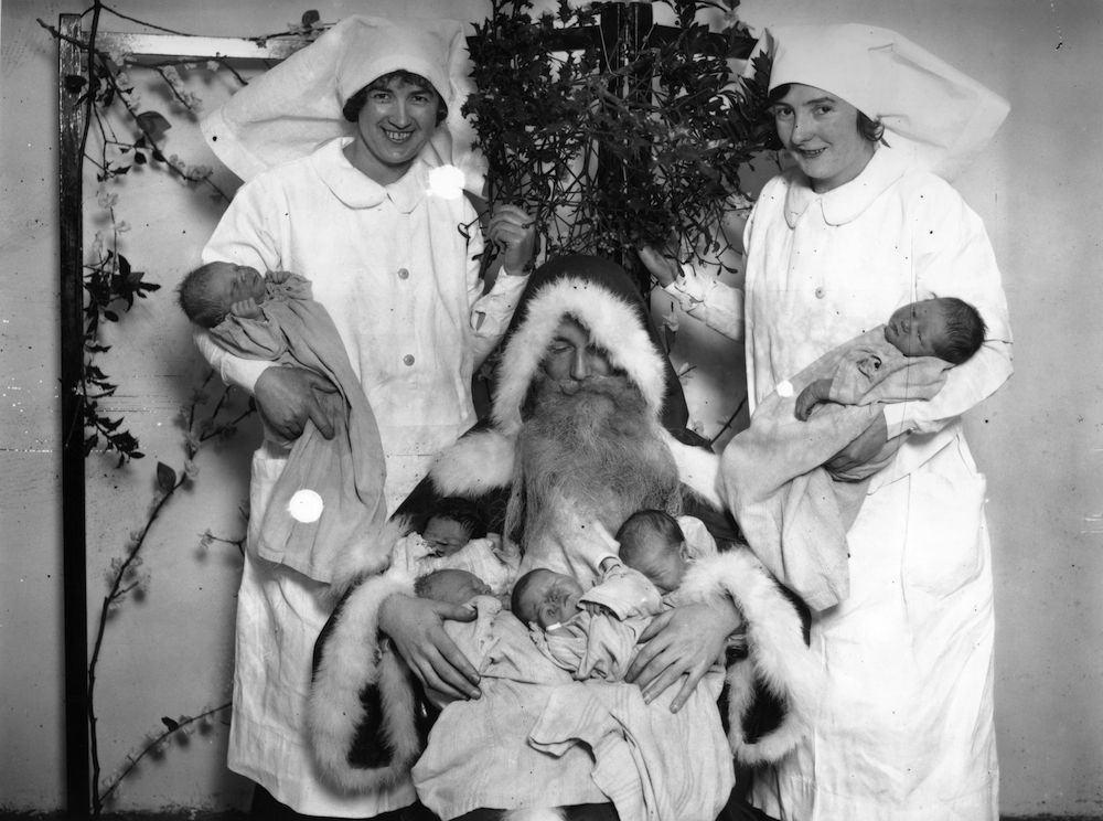 26th December 1929: Father Christmas with an armful of babies born on Christmas Day at London Maternity Home, City Road. (Photo by Puttnam /Topical Press Agency/Getty Images)