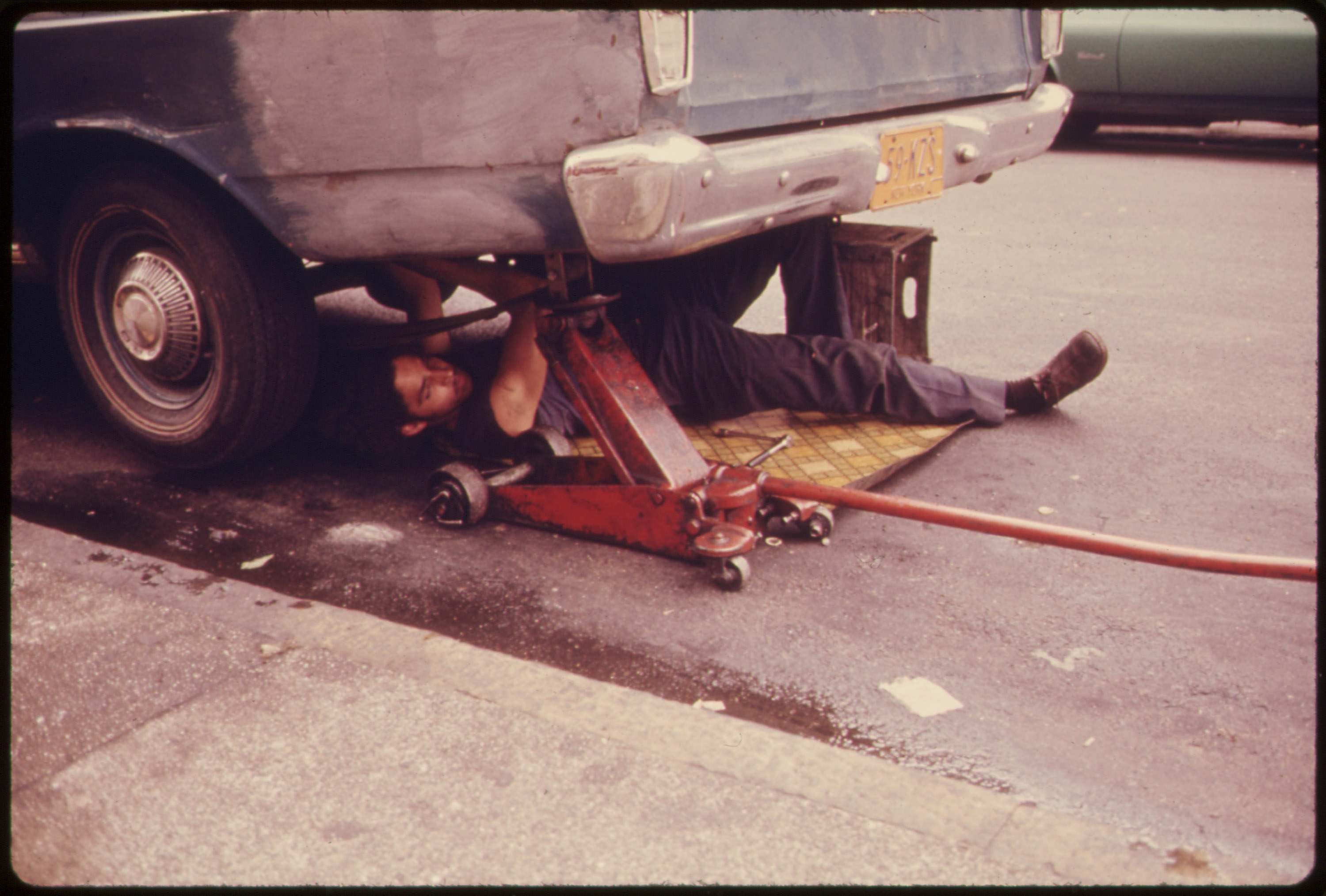 Man working on his car in Hell's Kitchen, NYC, June 1974.