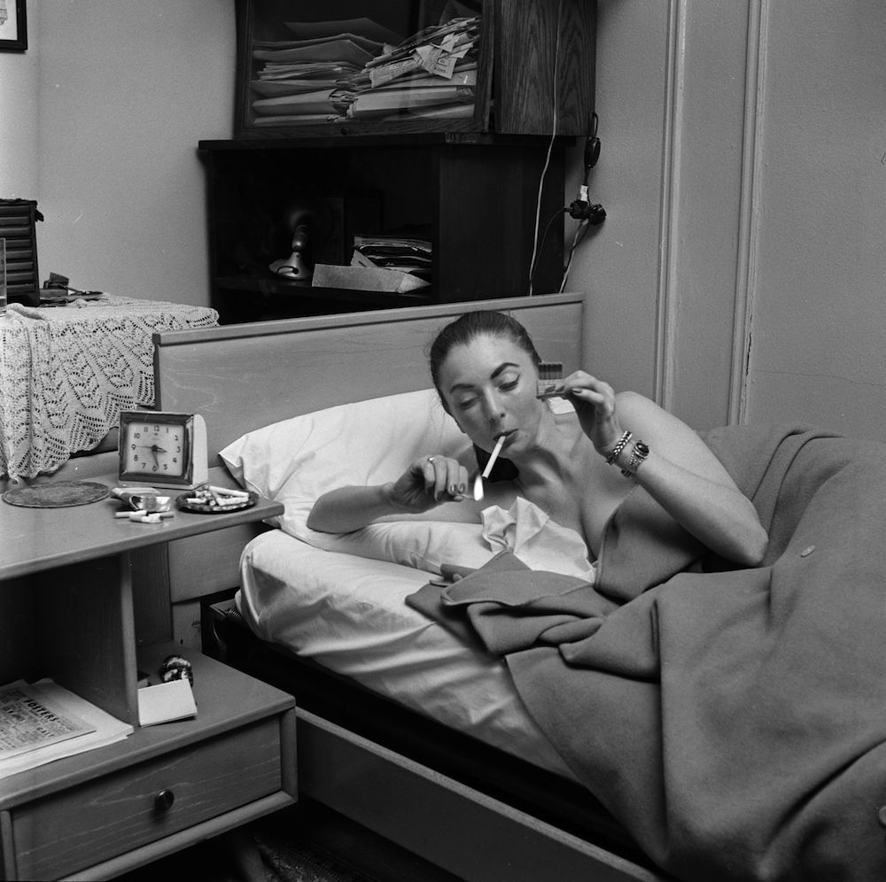 circa 1955: A member of a teenage girl gang lying in bed smoking a cigarette. (Photo by Vecchio/Three Lions/Getty Images)