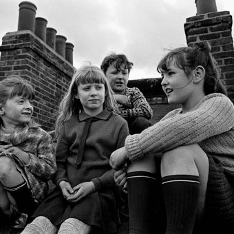 Children gossiping on the roof of their tenement block, Wandsworth ...