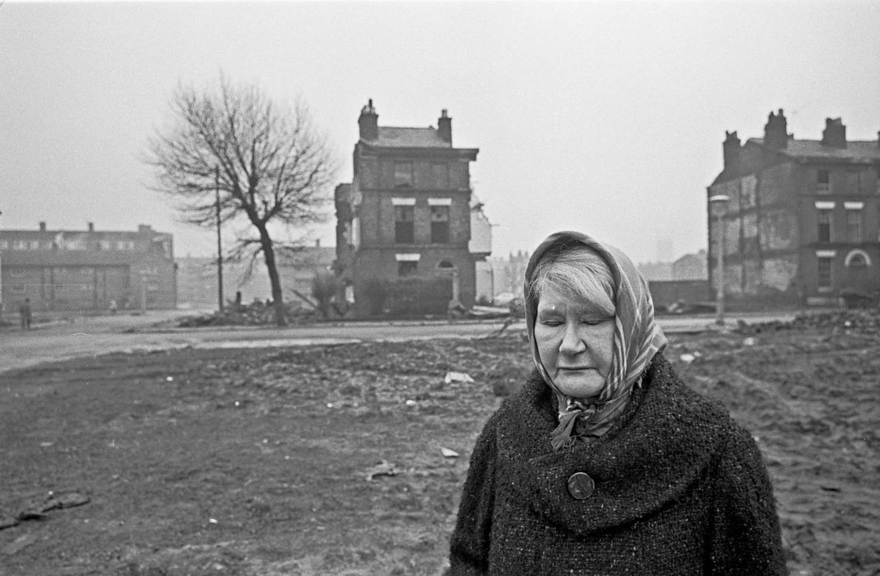 Elderly woman standing amidst slum clearance site Liverpool 8 1969 10-4