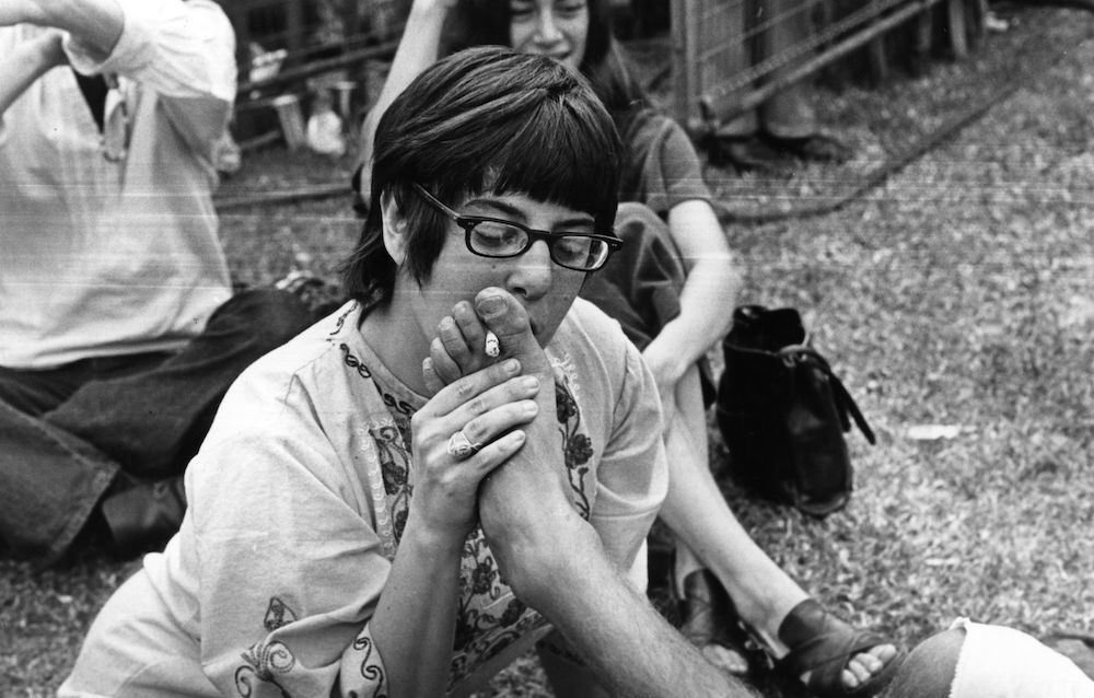 A music fan smokes a cigarette held in friend's toes at a rock concert in London's Hyde Park. (Photo by John Minihan/Getty Images)