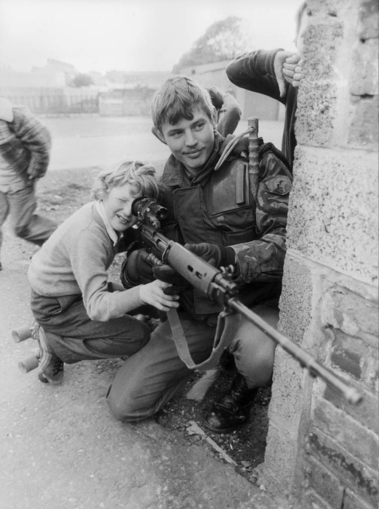 13th May 1981: A British soldier lets a young boy look through the sights of his rifle in Belfast. (Photo by Central Press/Getty Images)