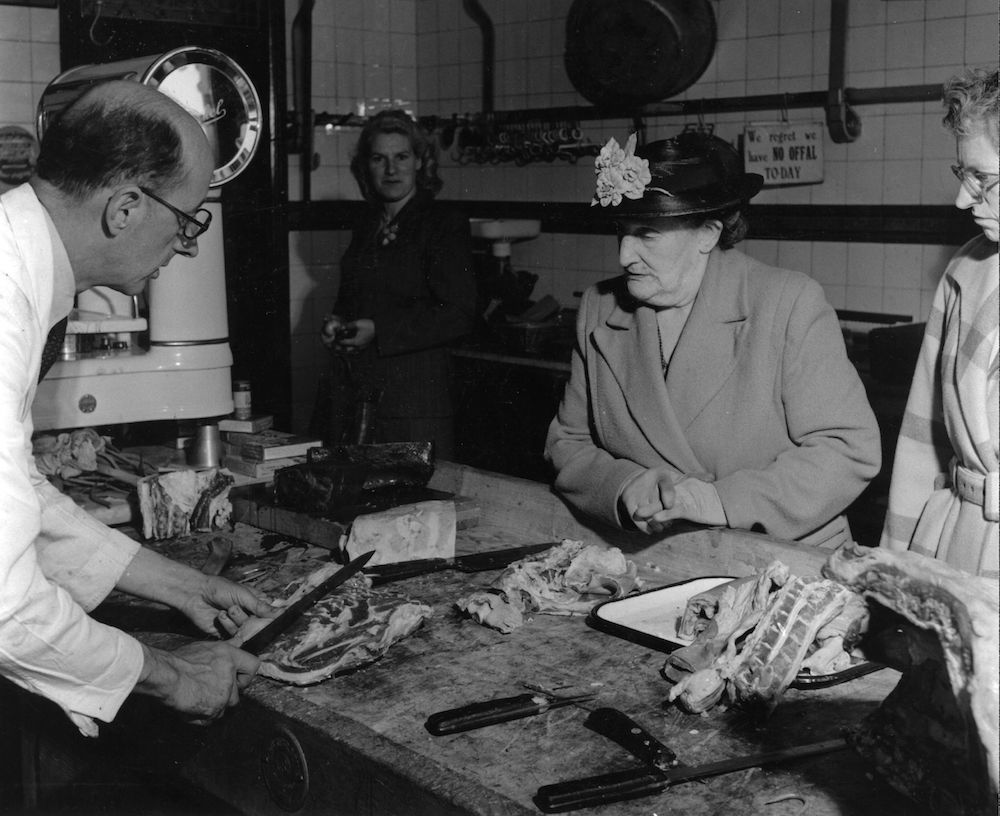 circa 1954: A woman customer watches the butcher slice-up a joint of meat. (Photo by Hulton Archive/Getty Images)