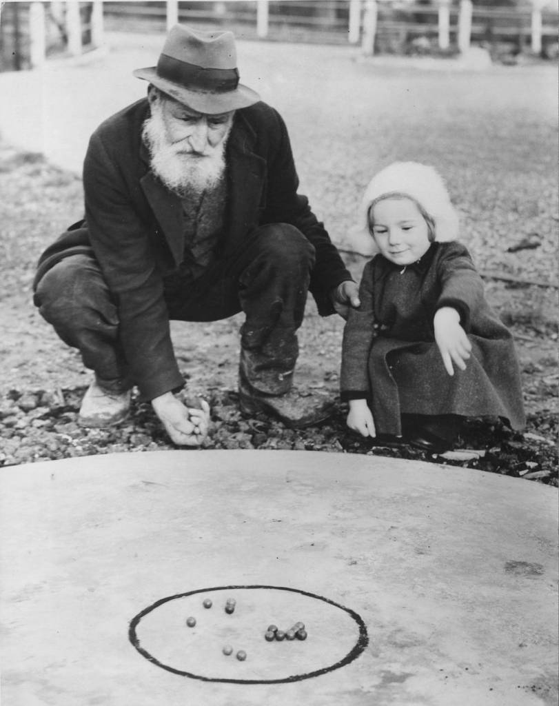 7th February 1938:  Both young and old are keen on the game of marbles at Tinsley Green in Sussex, where the World Marble Championship will be held, in front of the Greyhound Inn. Sam Spooner, 82, who won the championship more than 50 years ago, with Diana Winters aged two, who is already learning the game.  (Photo by Fred Morley/Fox Photos/Getty Images)