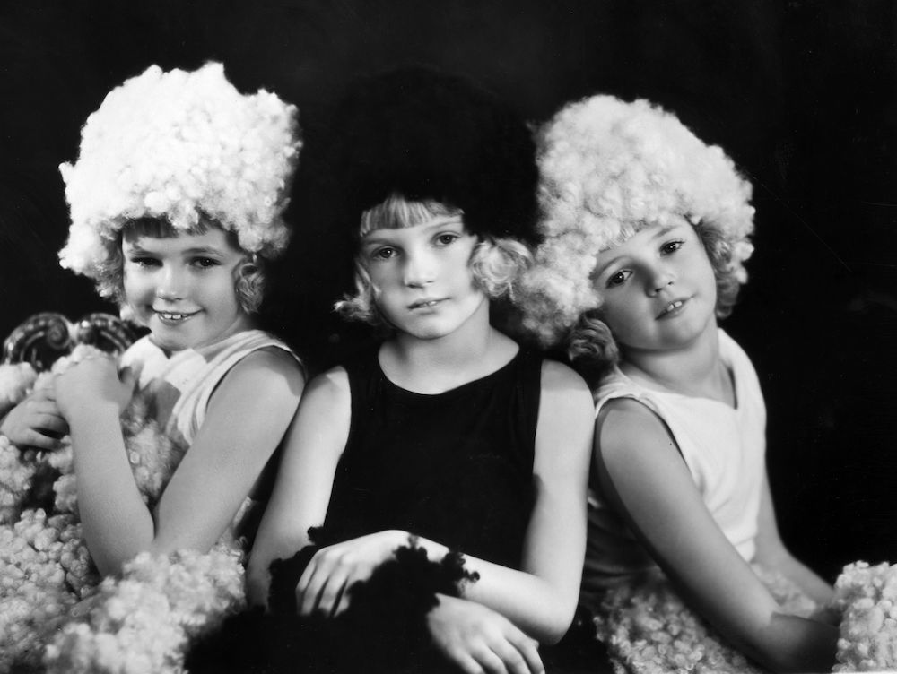 28th April 1930: Three child actresses wearing costumes depicting Wool in the 'Pageant of Britain and her Industries' in aid of the British Legion at the London Pavilion. The costumes are designed by Barbara Cartland. From left to right, they are triplets Claudette, Angela and Claudine Mawby. (Photo by Sasha/Getty Images)
