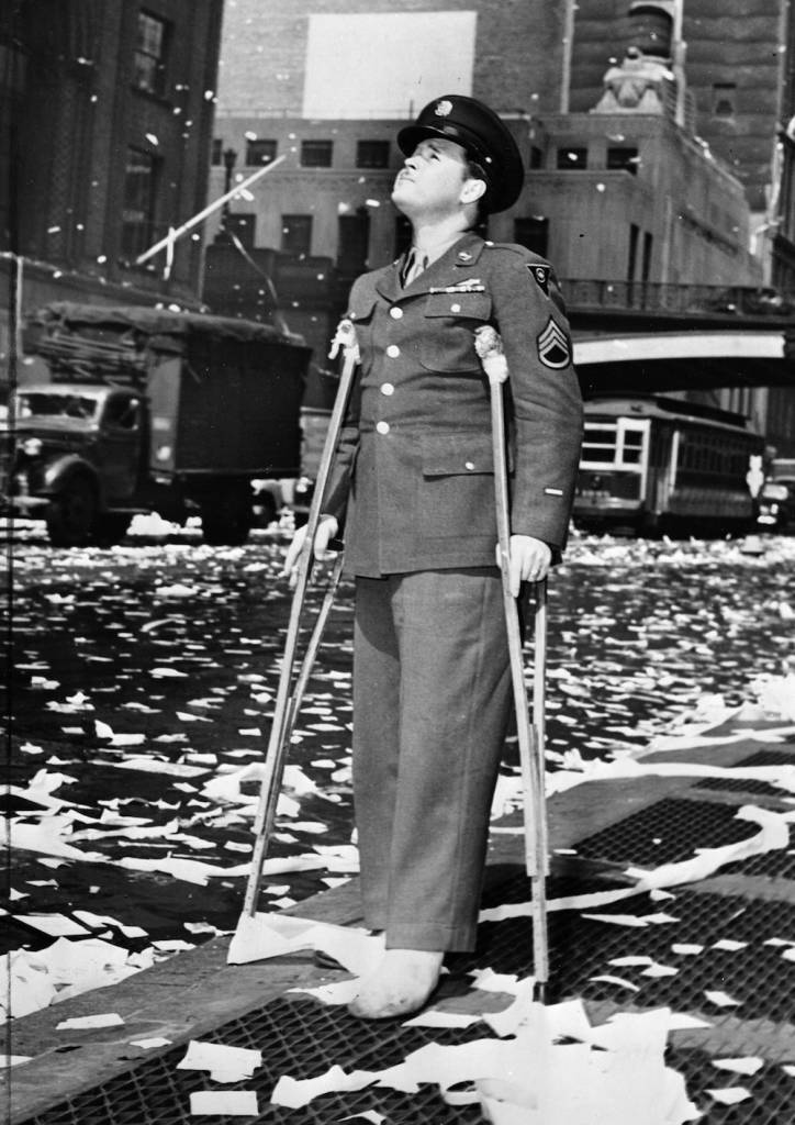 7th May 1945:  A wounded American serviceman during a ticker tape parade in New York following press reports of the unconditional surrender of Germany.  (Photo by Fox Photos/Getty Images)
