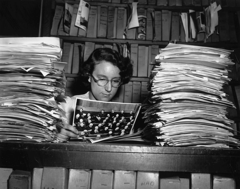 November 1951: A woman working at the Keystone Press Agency picture library with two piles of photographs. (Photo by Fred Ramage/Keystone Features/Getty Images)