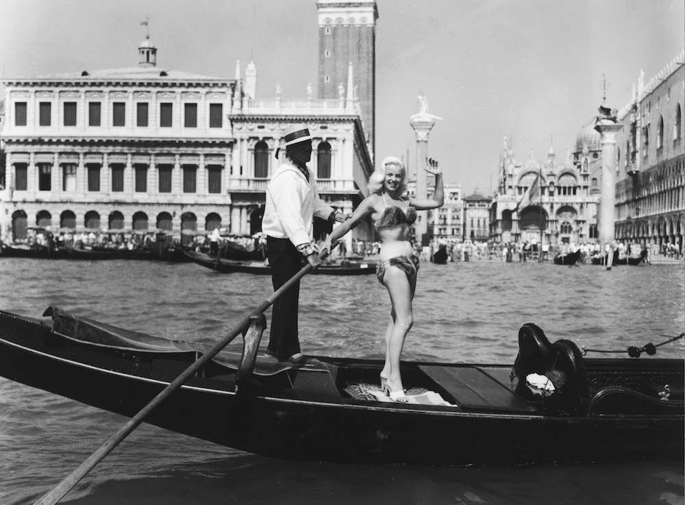 British actress Diana Dors (1931 - 1984) wearing a mink bikini whilst riding in a gondola past St Mark's Square, Venice during the Venice film festival, 5th May 1955. (Photo by Horace Abrahams/Keystone/Hulton Archive/Getty Images)