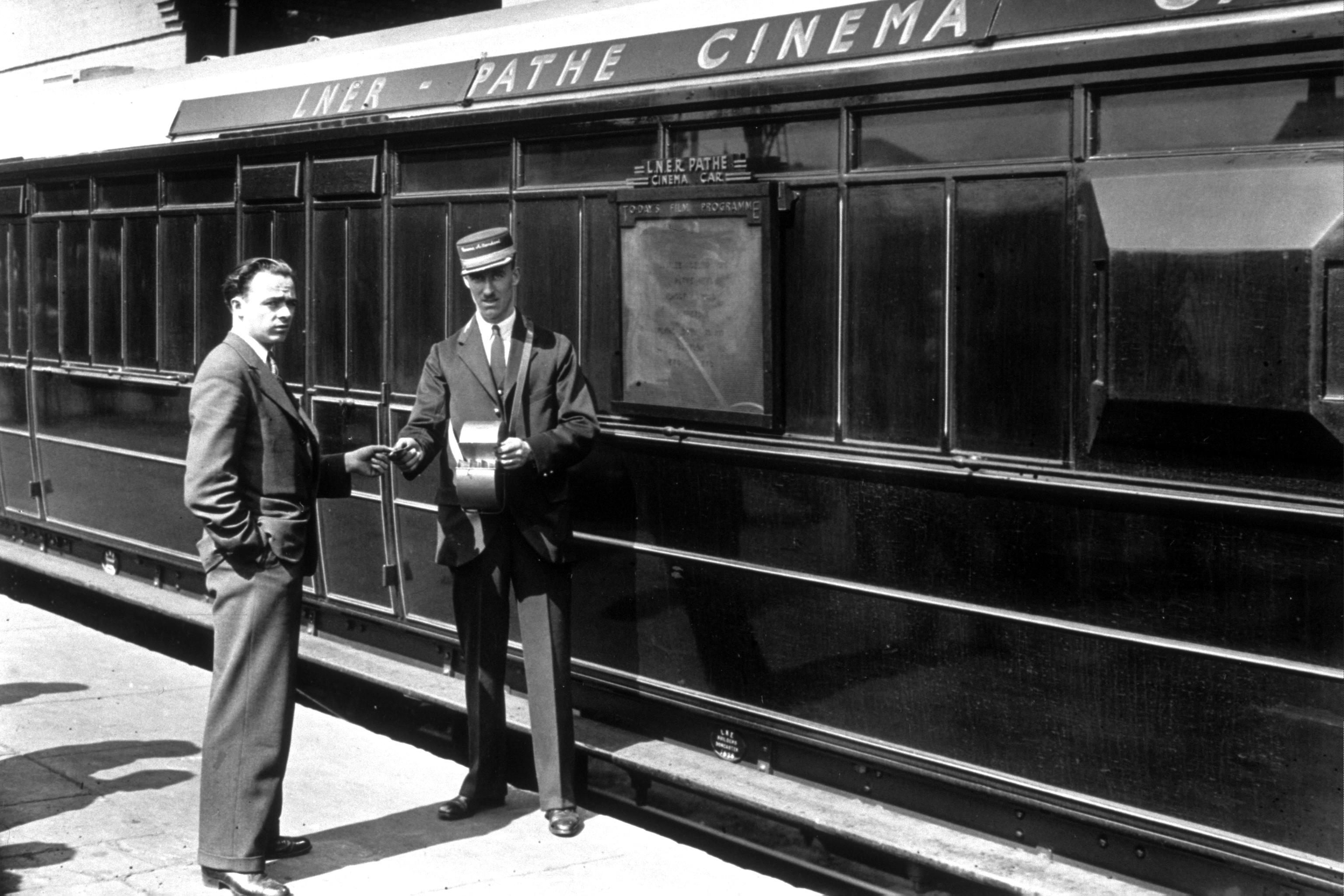 1938: A cinema attendant giving a ticket to a passenger for the Pathe cinema car, which ran on LNER trains. (Photo by Topical Press Agency/Getty Images)