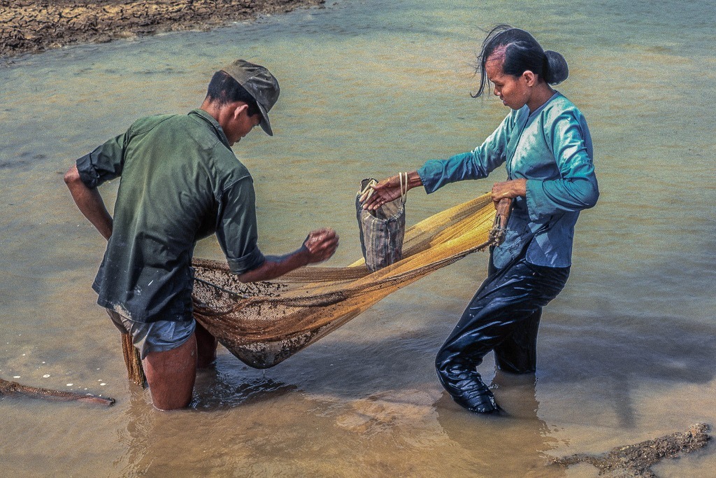 ARVN soldier and his wife gleening the last fish from the drying rain ponds by the Binh Duc air strip west of My Tho in 1969. (Dinh Tuong Province, Vietnam) (scanned colour slide)