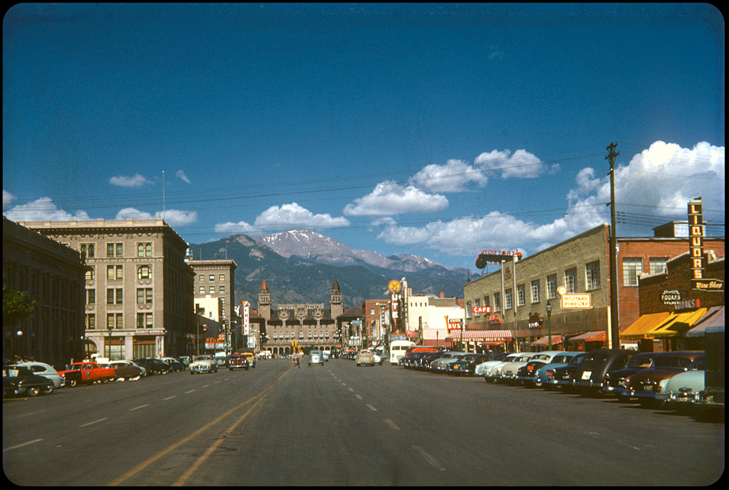 Colorado Springs 1952 The Antlers Hotel sit in front of Pike's Peak (and at the end of Pike's Peak Ave.) in the middle of a big-sky beautiful day. No less than 3 theaters are visible, all with great graphics and neon. The Ute advertises Pat and Mike with Spencer Tracy (1952). Across the street, the Peak is showing Retreat, Hell! (1952) with Frank Lovejoy.