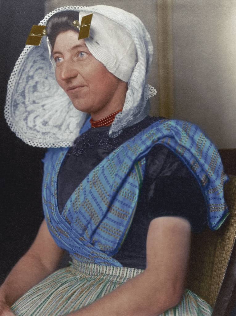 c. 1910 "Dutch woman." The large bonnet which arguably is one of the most recognisable aspects of Dutch traditional dress was usually made of white cotton or lace and sometimes had flaps or wings, and often came with a cap. The square stukken and golden pins denoted her marital status and that she was a Protestant. The rest of the costume, again like so many others came in distinctly regional variations were made from cotton, linen or wool, decorated with embroidered floral patterns. A sleeved bodice covered the top half of the body and came in a dark colour, contrasted by a colourful tunic as seen in this photograph.