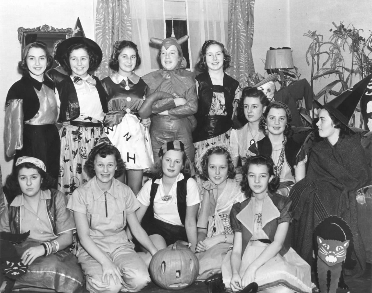 Miss Peggy Grumbling, in the standing row in "Devil" costume, played hostess to several of her friends at this pre-Halloween costume party, held at the home of her parents, Mr. and Mrs. Alfeus Grumbling. Second from left in the standing row is Betty Wilbur. Seated in the front, beginning at second from the left, are Charlotte Dowling, Betty Magnuson and Elnor Deimer. The girls had a buffet dinner and played Halloween games. (T. Times 10/31/1838, pg. 11)