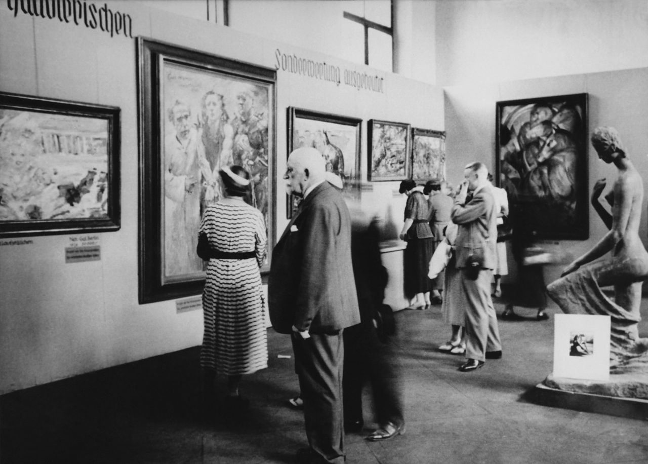 Visitors look at works in the Degenerate Art exhibition in Munich, which opened on July 19, 1937. Pictured are Lovis Corinth's Ecce homo (second from left) and Franz Marc's Tower of the Blue Horses (wall at right), next to Wilhelm Lehmbruck's sculpture Kneeling Woman.