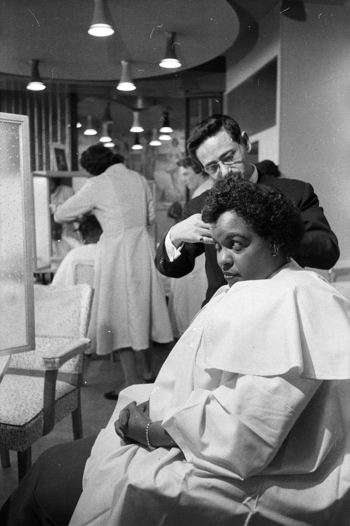 30th April 1957: A customer has her hair straightened out at pianist Winifred Atwell's hairdressing salon in Brixton, London. (Photo by Lee Tracey/BIPs/Getty Images)