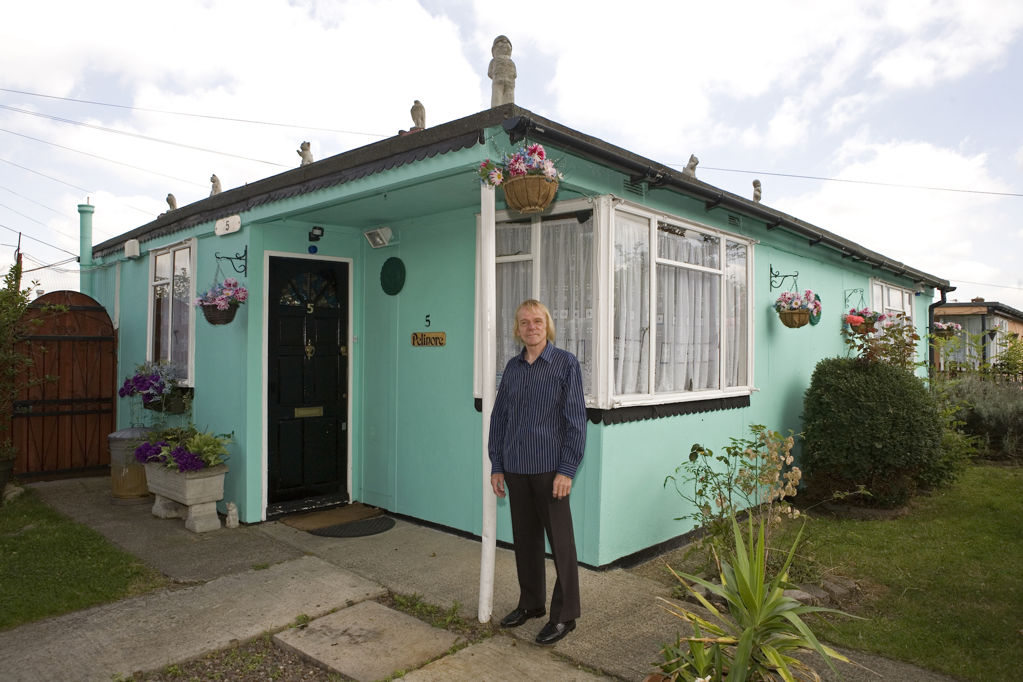 Jim Blackender in front of his prefab in 2009. Jim fought and lost. He raised an army of residents to save the prefabs from demolition but the battle ended up in a ballot which led by 54% to 46% to the 'regeneration' of the estate. By regeneration, the council means demolition of the post-war bungalows and replacement with double and triple storeys dwellings. The idea is to triple the density of the population but it's difficult to find out more as Lewisham is remaining very discreet about the future. The demolition process should have started in October 2012 but in June 2013, it still hadn't begun. On the estate, more and more prefabs are being boarded up. Residents were hoping they would be rehoused in new houses at the same location but it doesn't look like it will happen, so they are ending up accepting other housing options offered by the council as Jim and his wife Lauren did. In September 2012, they left their prefab for good for a 2 bedroom attached house in Rochester, Kent. I paid them a visit in Winter 2013. They both became very emotional when talking about their prefab. The scar hasn't healed yet. 'In a prefab, youíve got a two-bedroom detached property and unless you have lots of money, youíre never ever going to get that again. It was something we were fortunate to have as council tenants. Once the prefabs are gone, theyíre gone forever; youíre never going to get back to a place like that. I liked everything about the prefab ñ I couldn't put a finger on it. It was the people, the location. When we moved in 20-odd years ago, there was a really strong community, and there was no way anyone could have taken that place from the residents. But itís been left to rot, the Council should have been carrying out repairs, painting and redecorating, so people would want to live there, but hardly anything has been done to the estate. Itís depressing to watch it fall into disrepair'.