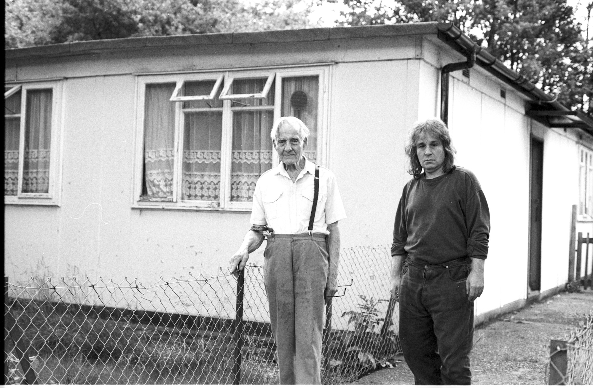 Peckham, South London, is where my prefabs journey starts. Well, my London one. I read an article about home parks in the Big Issue and wanted to go and photograph one. 'Why do people live in mobile homes, caravans, prefabs?' is a question I have always asked myself. I was talking to a colleague at the French school where I used to work about this idea of doing a piece about a park home outside London. 'You don't need to go that far' she says, 'there are some sorts of mobile homes where I live down in Peckham. Come round and I'll show you'. Which I did... I found myself in front of a row of prefabs. What were they still doing here? Still standing and very much lived-in? I knocked on a door. An old man opened and asked me what the purpose of my visit was. I said I was a French photographer interested in his little house. Could he tell me more about it? He invited me in for a cup of tea and started to tell me what he knew about the history of Britain post-war prefabs. He became particularly talkative when he found out I was from Normandy, where he had landed in June 1944. He proudly showed me his prefab. Although he didn't wish to be photographed, the time I spent with him was a wonderful introduction to the world of post-war prefabs. Stanley and Ted, father and son outside their prefab on Kimberley Avenue. I haven't got any picture of their interior for a good reason: they freaked me out... When I knocked on their door back in 2002, Ted invited me in, showed me his living-room and shut the door behind me. I panicked for a few seconds. I was in the filthiest place I had ever seen. The floor and the furniture were all covered with newspaper, there was dog poo about everywhere and behind the kitchen door, I could here the dog barking. I felt trapped. How to escape? Lucky me, Ted didn't want me any harm. I can't remember exactly what happened but I must have found an excuse and he let me go. It was one of the only times I said no to a cup of tea in a prefab.