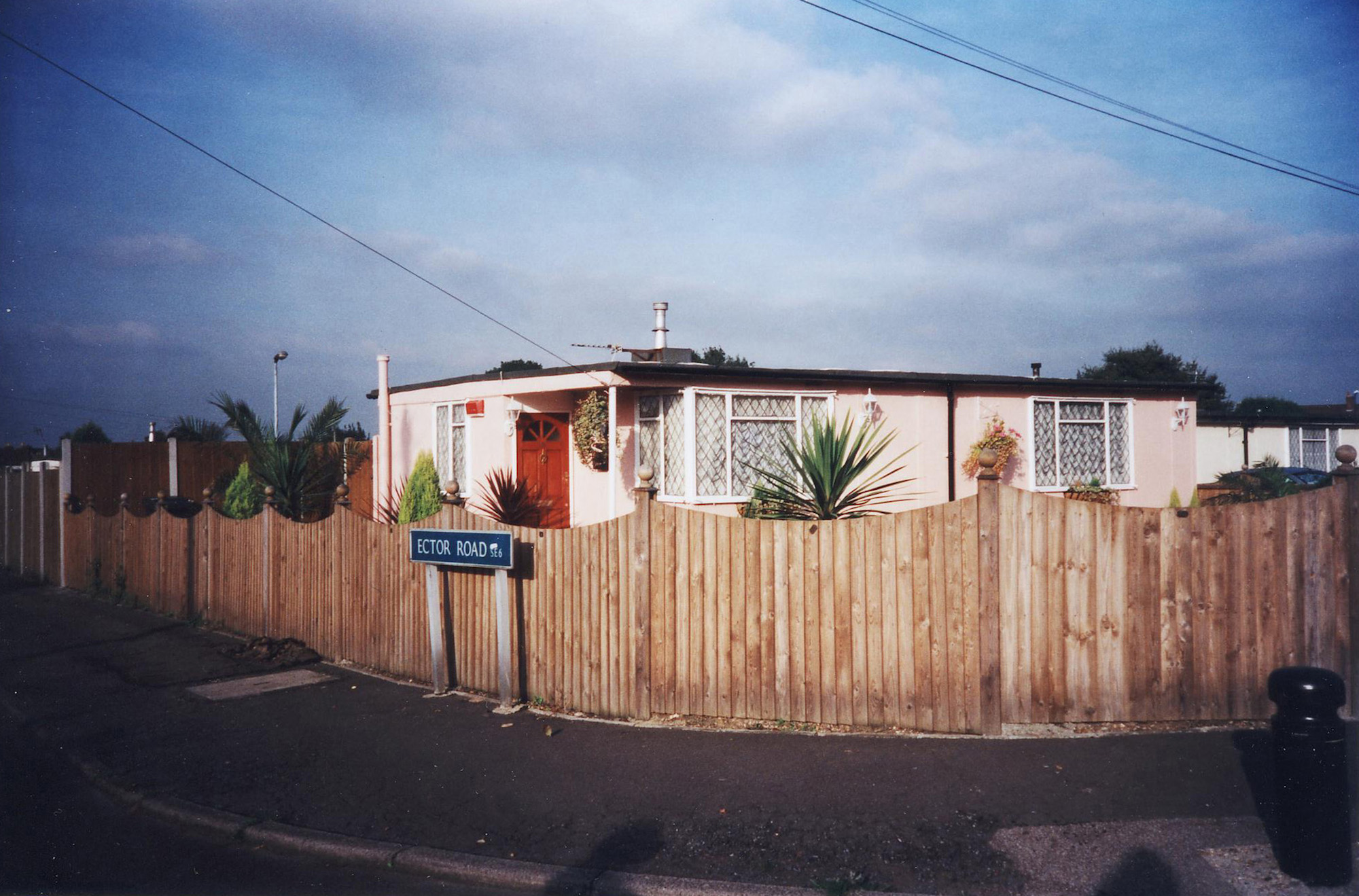 The Catford prefabs estate in South London, 2004. Thousands of post-war prefabs are still being lived in and cherished by their tenants or owners all over the UK. I love prefabs. Some people will think living in a prefab is like living in a box. Yes, it might sound or even look a bit like that but what a lovely, sophisticated box! I am talking about post-war prefabs, erected in a hurry just after the war when Britain was suffering an unprecedented housing shortage. More than 150 000 of these prefabricated houses were erected all over the UK mainly ins small estates. They were luxury to most of the residents who mainly were service men coming back from the war and reuniting with their family. Their prefab became their little castle with all mod cons and even more than any working class could hope for at the time: hot water, toilets inside, a fitted kitchen with a gas fridge and a garden all around the house. Part of the temporary housing programme, they were not supposed to last over a decade. Yet, over 70 years later, a few Thousands are still standing and very much loved. Why do people love their prefab so much, why are they so attached to their "cardboard or tin boxes"? Is it the layout of the prefab, the design of the interior, the garden around? Is the sense of community they created? Or a combination of everything?That's what I have been trying to find out for the last 11 years, since I started taking pictures of prefabs in South London. I have travelled all over the UK, from Redditch to Newport, Chesterfield, Catford and even on the Isle of Lewis to try to draw some answers. I have met wonderful people and come back with their portraits and their moving stories. Here they are for you to discover through this project.