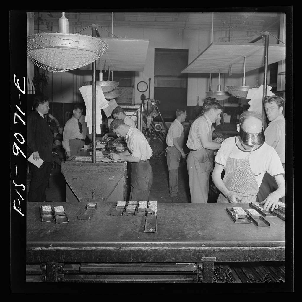 Composing room of the New York Times newspaper. Make-up men pick up linotype slugs from center table
