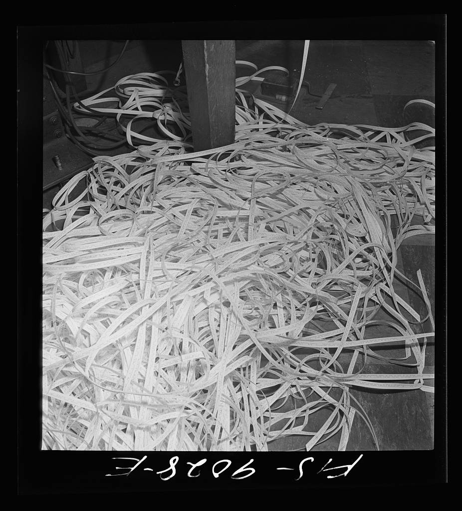 Radio room of the New York Times newspaper. Tape on which messages have been recorded in international Morse code piles up on floor