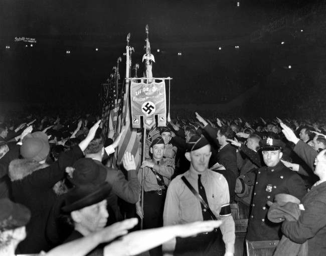 The crowd responds with a Hitler salute as uniformed members of a German-American Bund color guard march at a gathering in New York’s Madison Square Garden, Feb. 20, 1939.