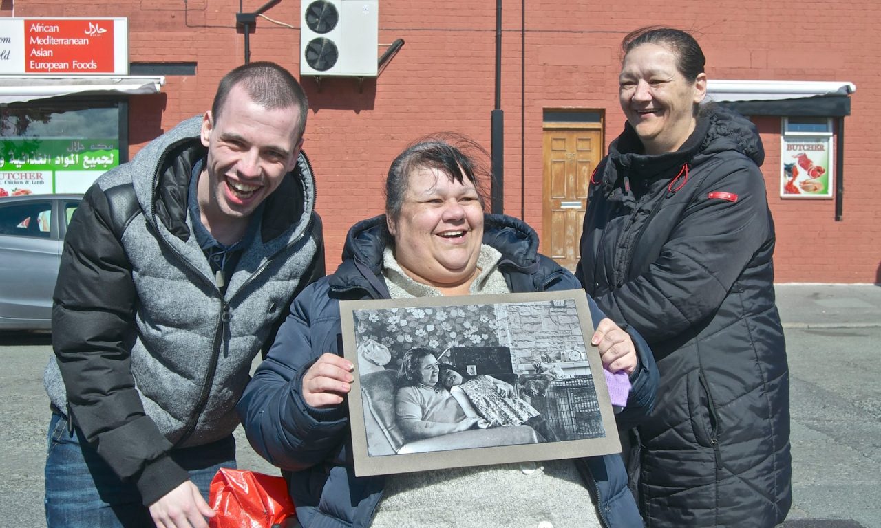 Lizzie, with her son and sister, holds the 1974 picture of her and her mother