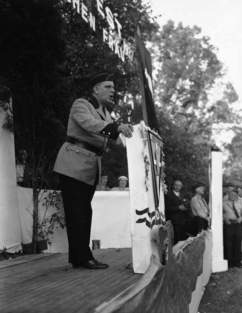 Answering charges that the German-American Volksbund is engaged in un-American activity, Fritz Kuhn, above, told thousands gathered camp Nordland, Andover, New Jersey on Sept. 26, 1937, the groups’ activities are founded on patriotic lines. He said the bund will continue its fight for Americanism until America is controlled by Americans and by a bunch of Russian-controlled Jews. American flags outnumbered swastikas, but there was goose stepping and Nazi saluting