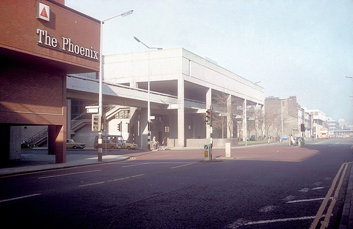 View of Oxford Road looking north towards Manchester City Centre, from the junction with Booth Street, 1976. Shows the Royal Northern College of Music (centre), with the high-level pedestrian walkway that was planned to link the educational institutions along Oxford Road.