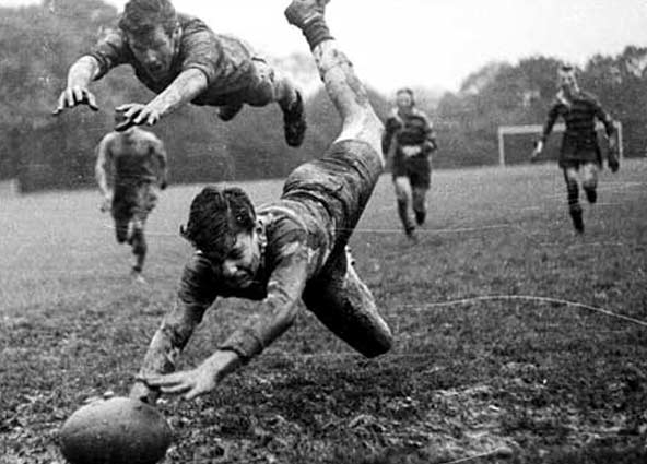 Svartvit bild med pojkar som kastar sig efter en rugbyboll