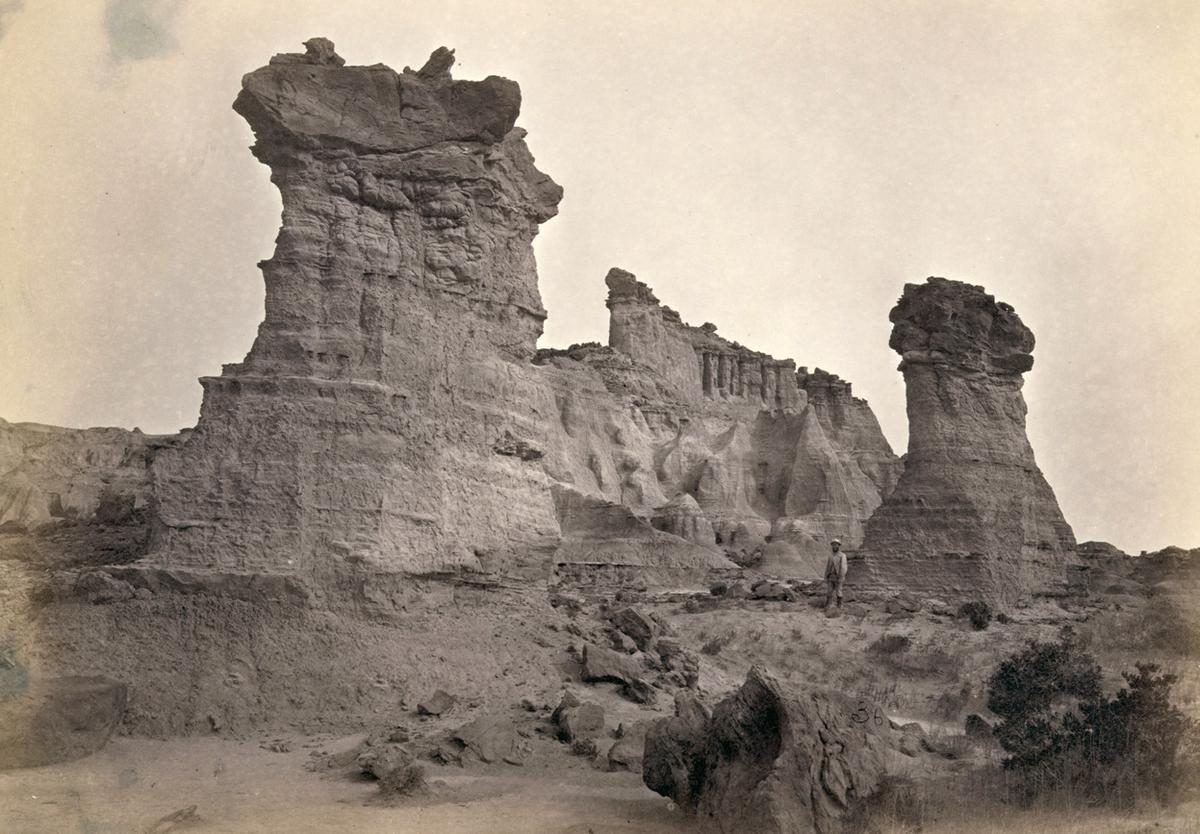 Rock formations in the Washakie Badlands, Wyoming, in 1872. A survey member stands at lower right for scale. 