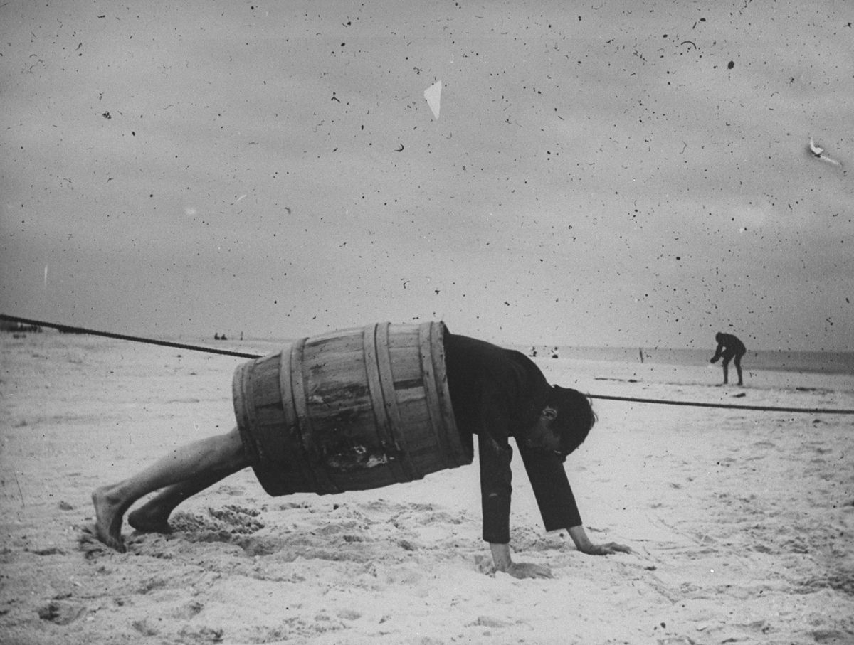 Sept. 8, 1897 A man in a barrel does a push up at the beach.