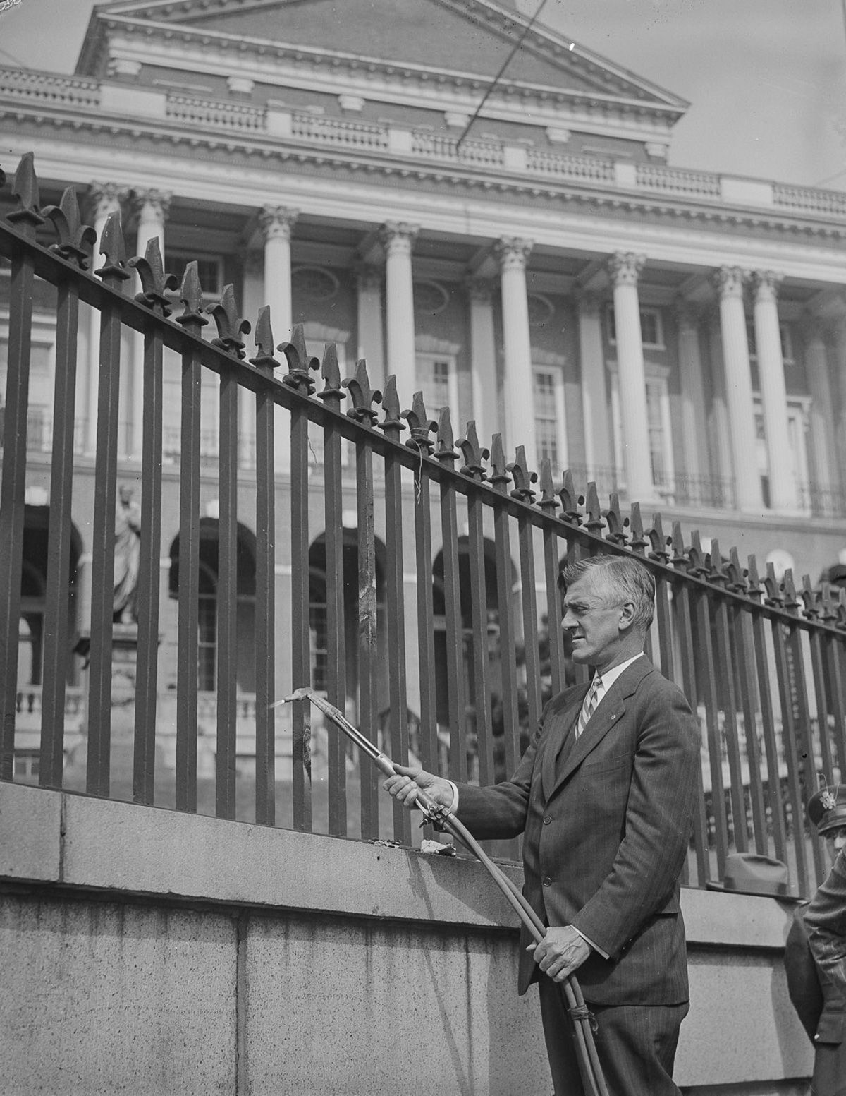 Oct. 5, 1942 Governor Leverett Saltonstall applies a blowtorch to the iron fence in front of the Massachusetts State House.