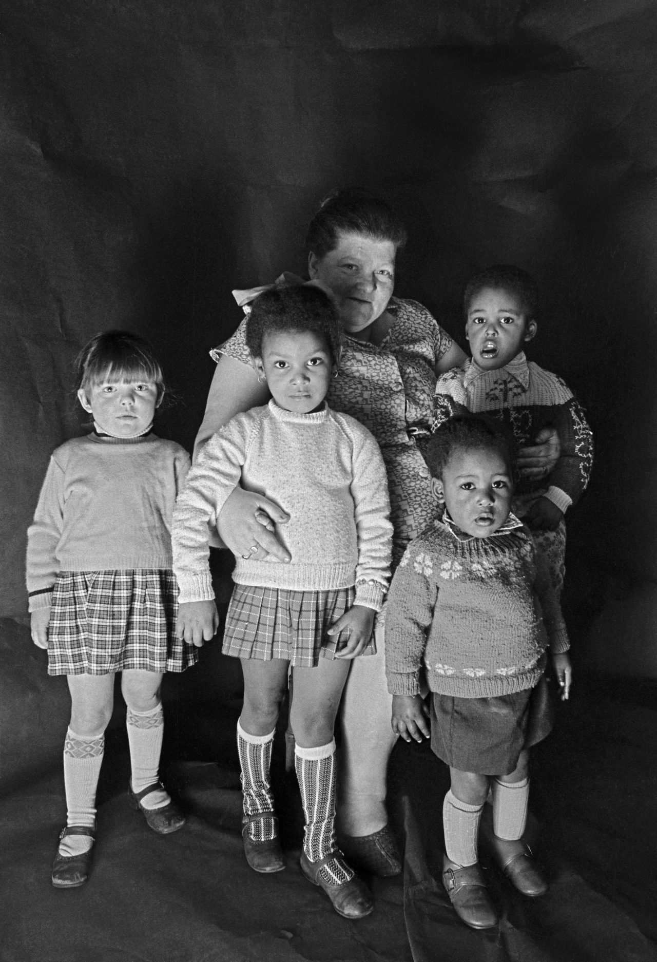 Portrait of a foster mother with children in Meadows's free photographic studio at no.79B Greame Street, Moss Side, Manchester, February - April 1972.