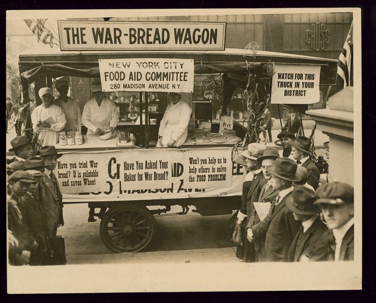Title: The war-bread wagon Creator(s): Underwood & Underwood, copyright claimant Date Created/Published: [Place not identified] : [Publisher not identified], [1917 October] Medium: 1 photograph : gelatin silver print ; sheet 20.2 x 25.4 cm. Summary: Photograph shows women cooks of the New York City Food Aid Committee demonstrating how to bake breads and other baked goods using wheat substitutes, such as corn and rye, as part of a conservation drive to save food for the war effort during World War I; they travel around New York City in a truck labeled "The War-Bread Wagon" and with signs that state "New York City Food Aid Committee 280 Madison Avenue N.Y.", "Watch for this truck in your district", "Have you tried War bread? It is palatable and saves Wheat", "Have you asked your baker for War Bread?", and "Won't you help us to help others to solve the Food Problem". The truck, parked on Fifth Avenue, has attracted a small crowd.