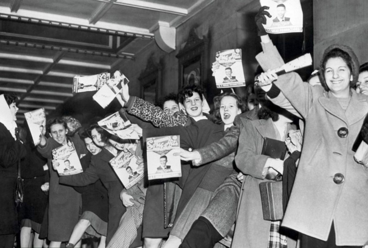 A line of teenage girls, holding Song Hits magazine, waiting for singer Frank Sinatra to arrive at the Paramount Theatre, New York, New York