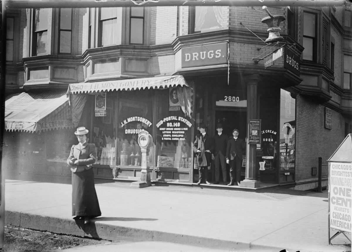 Unidentified men and woman standing at the entrance to J.H. Montgomery Drugs, Sub postal stationGeorge Silas Duntley Photographs 1899-1918