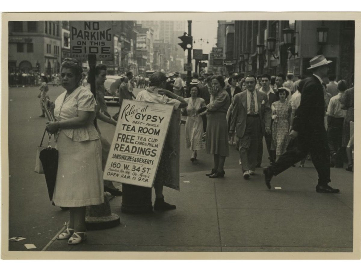 A man wears a sandwich board sign for Gypsy Tea Room on a busy street in Midtown Manhattan.1950