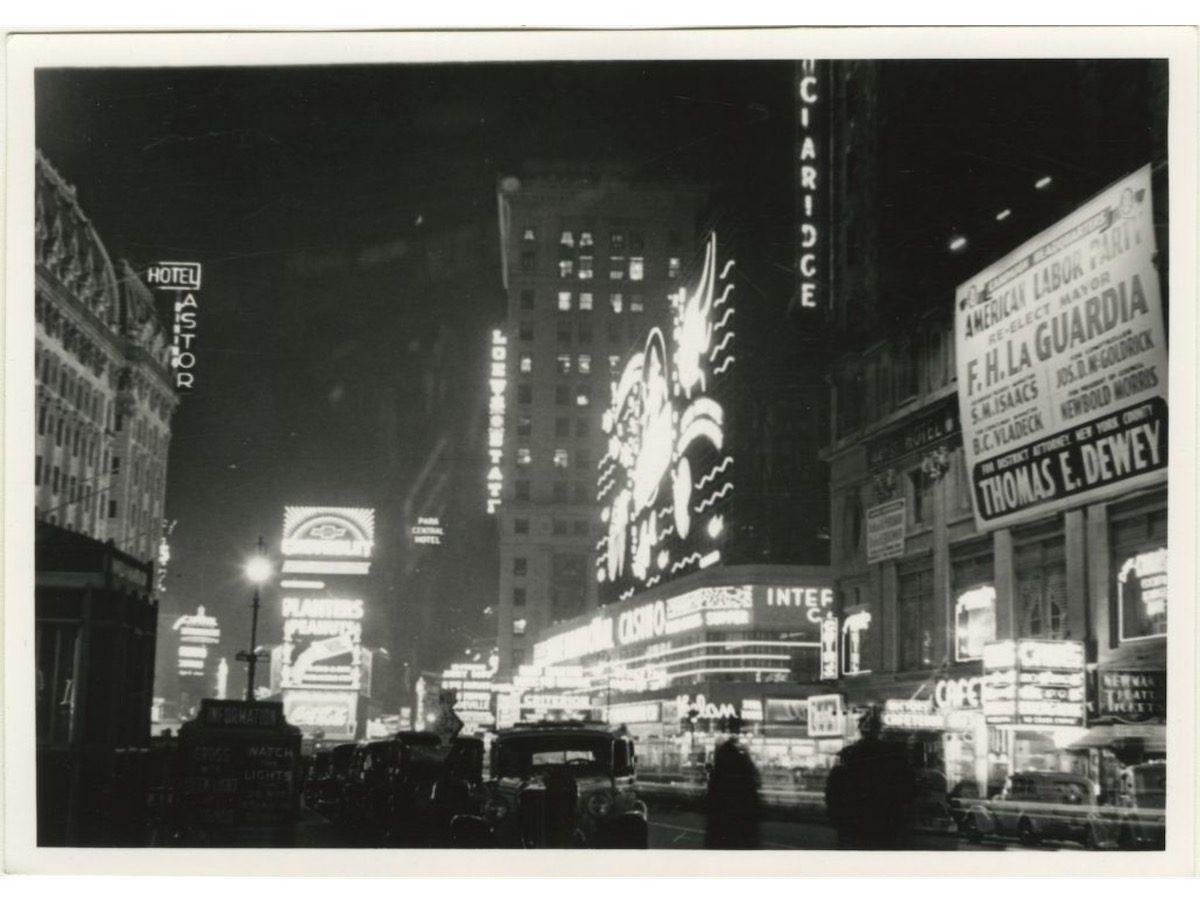 Broadway north of 42nd Street at night in Times Square with Astor Hotel to the left and an American Labor Union Party sign for Mayor F.H. La Guardia's re-election to the right.