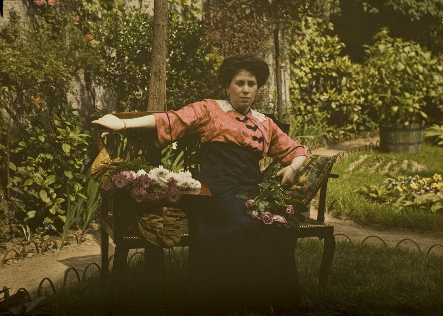 Charles Corbet, Mrs. Corbet on a gardenbench with a flowerbouquet c. 1910, autochrome