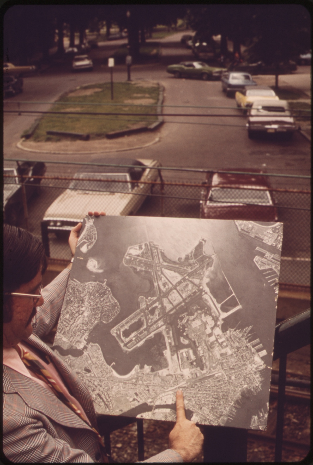 John Vitagliano, Manager of the East Boston Little City Hall and Chairman of the Winthrop Noise Abatement Committee, Points Out on Aerial Photograph the Section of Neptune Road and Logan Airport Runway 15r-33l that he Is Facing, Looking Southeast Down Neptune Road, 06/1973